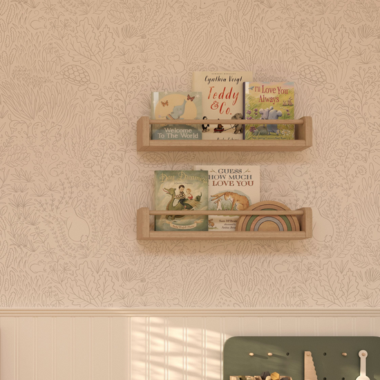 Showing a section of a wall and the top corner of a green wooden child's workbench with wooden tools. Wall is panelled in white at the bottom with our Garden Doodles wallpaper in grey above. On the wall art 2 Spice rack style shelves in light wood with books and a muted wooden rainbow stacking toy in. Wallpaper features woodland animals and foliage hand drawn in grey line detail on a neutral background.
