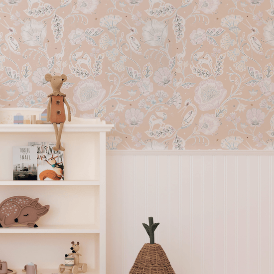A vintage off white bookshelf to the left of the image with traditional toys and books styles on each shelf and on top, and the top of the ferm living pear basket. In front of a wall panelled white a third of the way up, with our Woodcut Wonderland Calamine wallpaper above. Wallpaper features foxes, cranes, squirrels, and hares set against elegantly embellished foliage and blooms