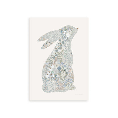Our Floral Bunny Art Print in Blue features a cute bunny sitting up with its back facing out so we can see it's tail, and it's head slightly turned towards the front so it's eye and nose can be seen. The Bunny has been drawn with ornate blooms and foliage filling it in, in blues and greens, on a neutral background.