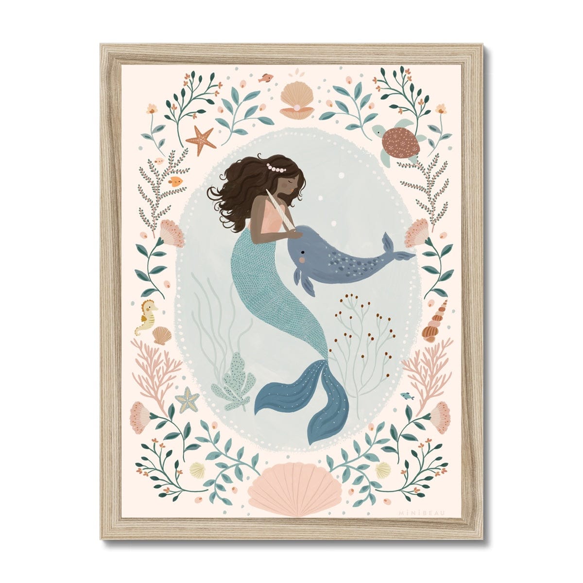 Beautiful dark skinned and haired mermaid with a pearl headband petting her friend Narwhal within a pale teal coloured oval background with white dots round the edge. On the outside of the oval is a sea themed border on a neutral background. The border consists of foliage, flowers and items you would find at the bottom of the sea, shells, turtle, sea horse with a large clam shell at the bottom, in a natural wood frame