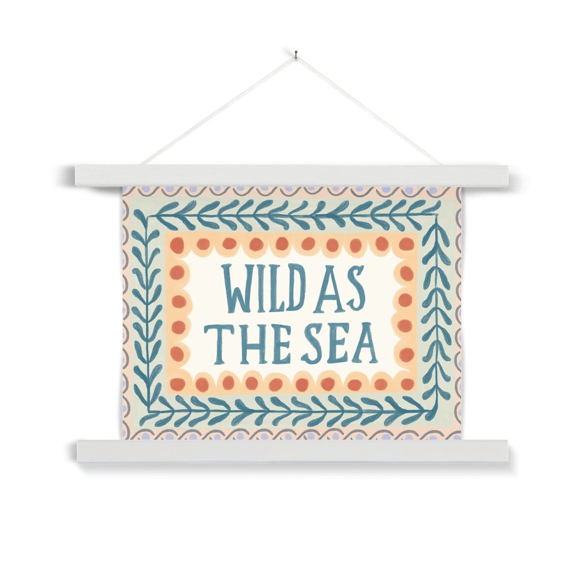 A typography print with the words WILD AS THE SEA in capital letters in watercolour deep teal in the middle on a neutral background, with 3 borders. The first being yellow scallops with deep orange dots, the second being foliage in the same colour as the typography on a pale green background and the outer being a sage wave pattern with lilac dots on a peach background hanging from a nail in a white wooden hanger