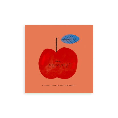 A red apple on a dark coral background with a blue leaf on the stalk. The words une pomme handwritten on the apple with *that's french for an apple written underneath