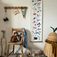 Animals of the world height chart hanging from a square wooden hook, next to a vintage wood coat hook rail, with a vintage wooden chair underneath with a plush tiger on, Shleich animals are on the floor with wooden alphabet blocks
