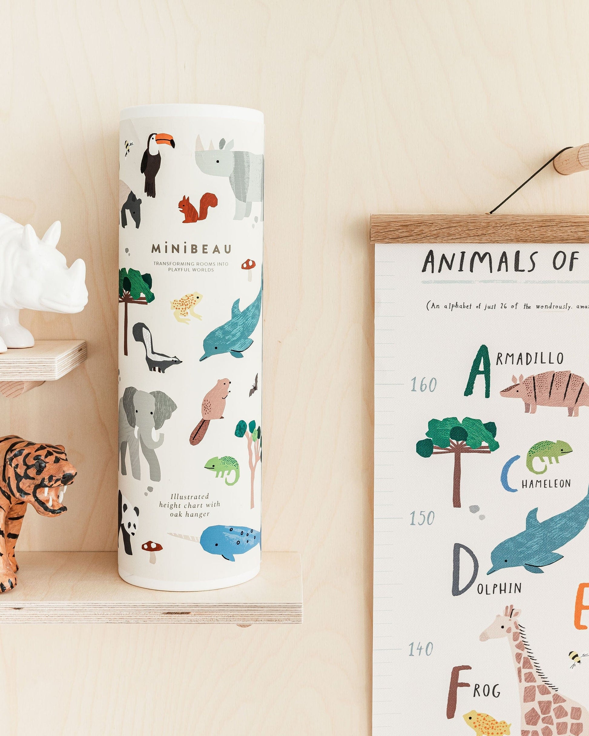 Photo showing the top left of the height chart hanging on the wall and the gift packaging tube decorated with animals from the height chart on