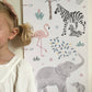 Close up of a girl standing next to the Serengeti height chart. Showing the elephants, flamingo and zebras in detail.