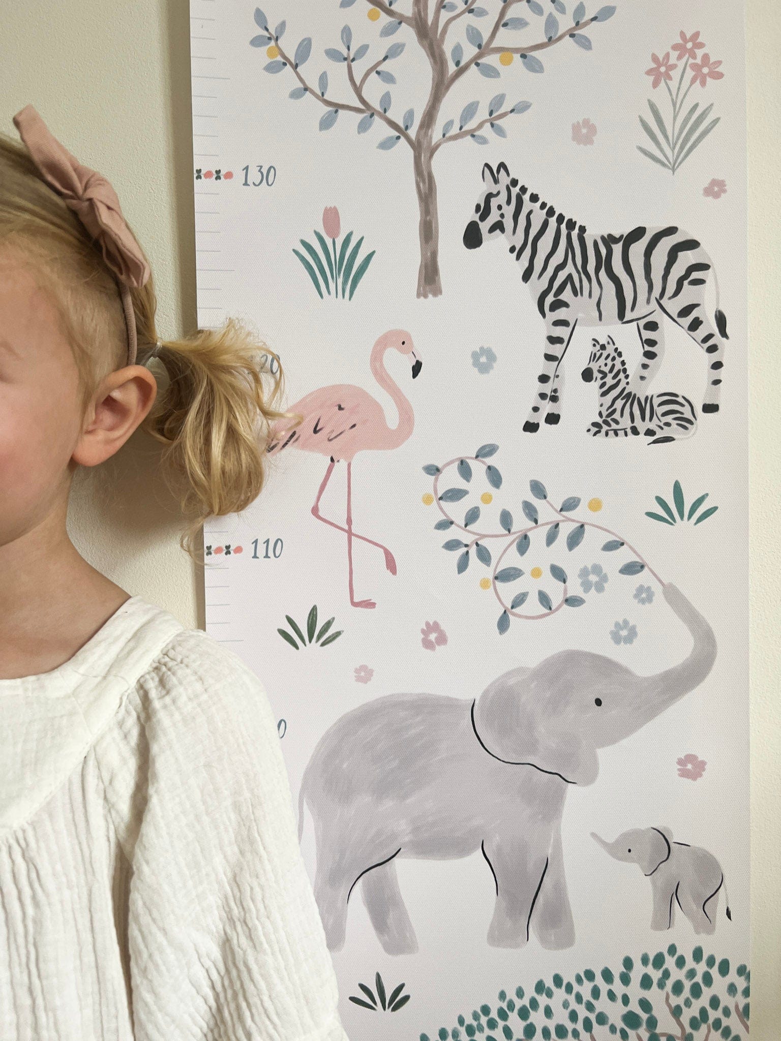 Close up of a girl standing next to the Serengeti height chart. Showing the elephants, flamingo and zebras in detail.