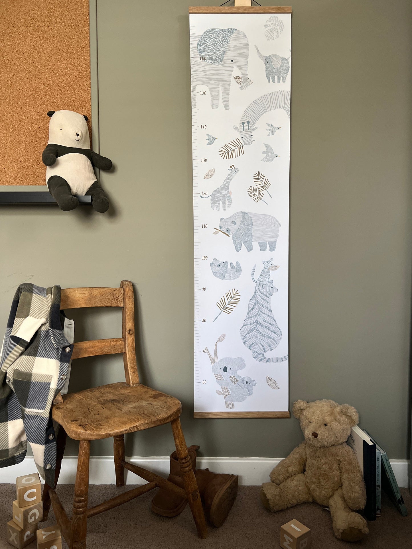 Stripey Safari Height Chart hanging on a green wall next to a vintage wooden child's chair and a teddy on the floor.