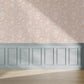 Wallpaper sample with a peach background and white animals such as storks and wolves with pretty floral patterns.